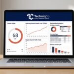 Close-up of a laptop on a clean wooden office desk displaying the TechniqCo domain rating analytics dashboard with DR scores, backlink growth graphs, and referring domain metrics in coral-orange and dark navy brand colors